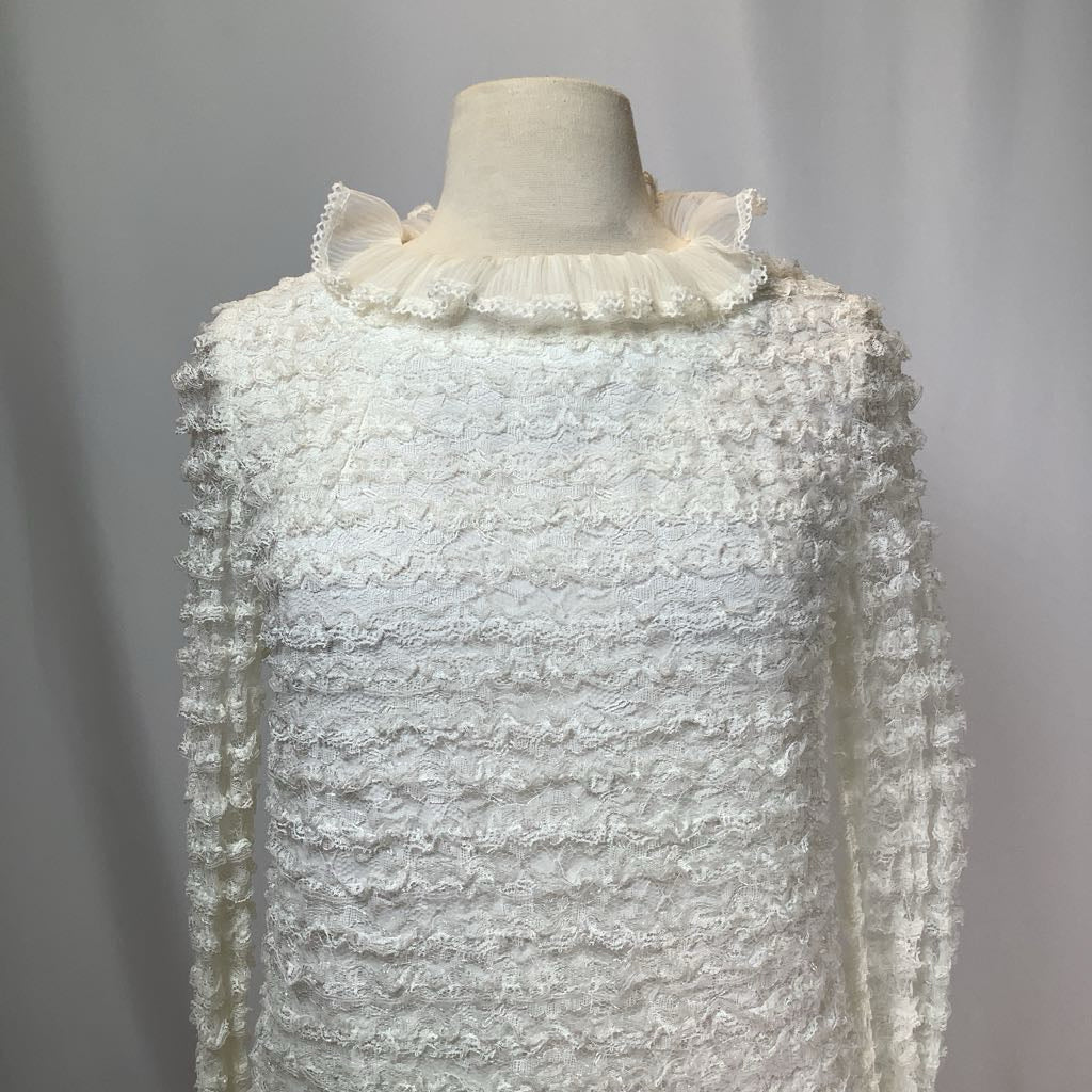 White textured dress on a mannequin against a plain background