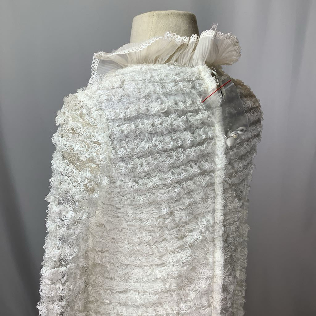 Mannequin wearing a textured white dress with lace details against a gray background