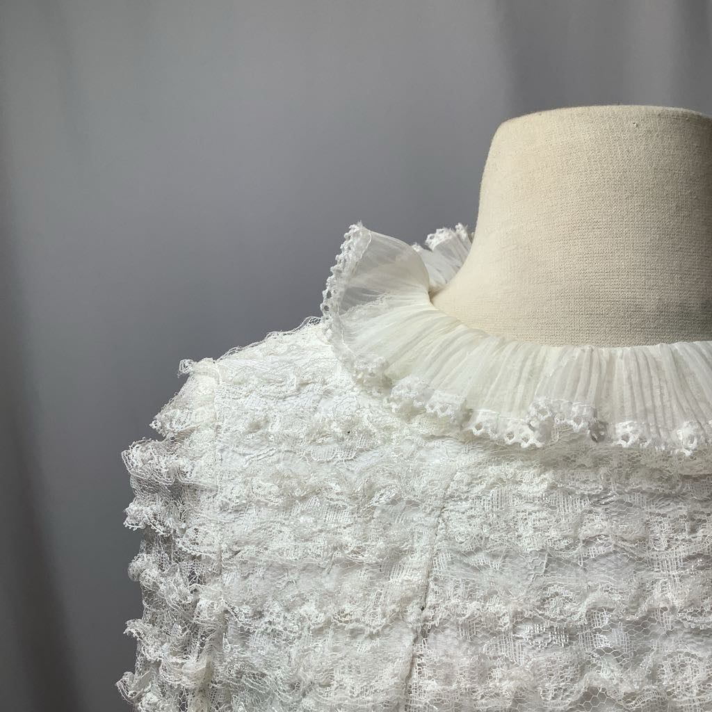 Mannequin wearing a white lace dress with a plain background