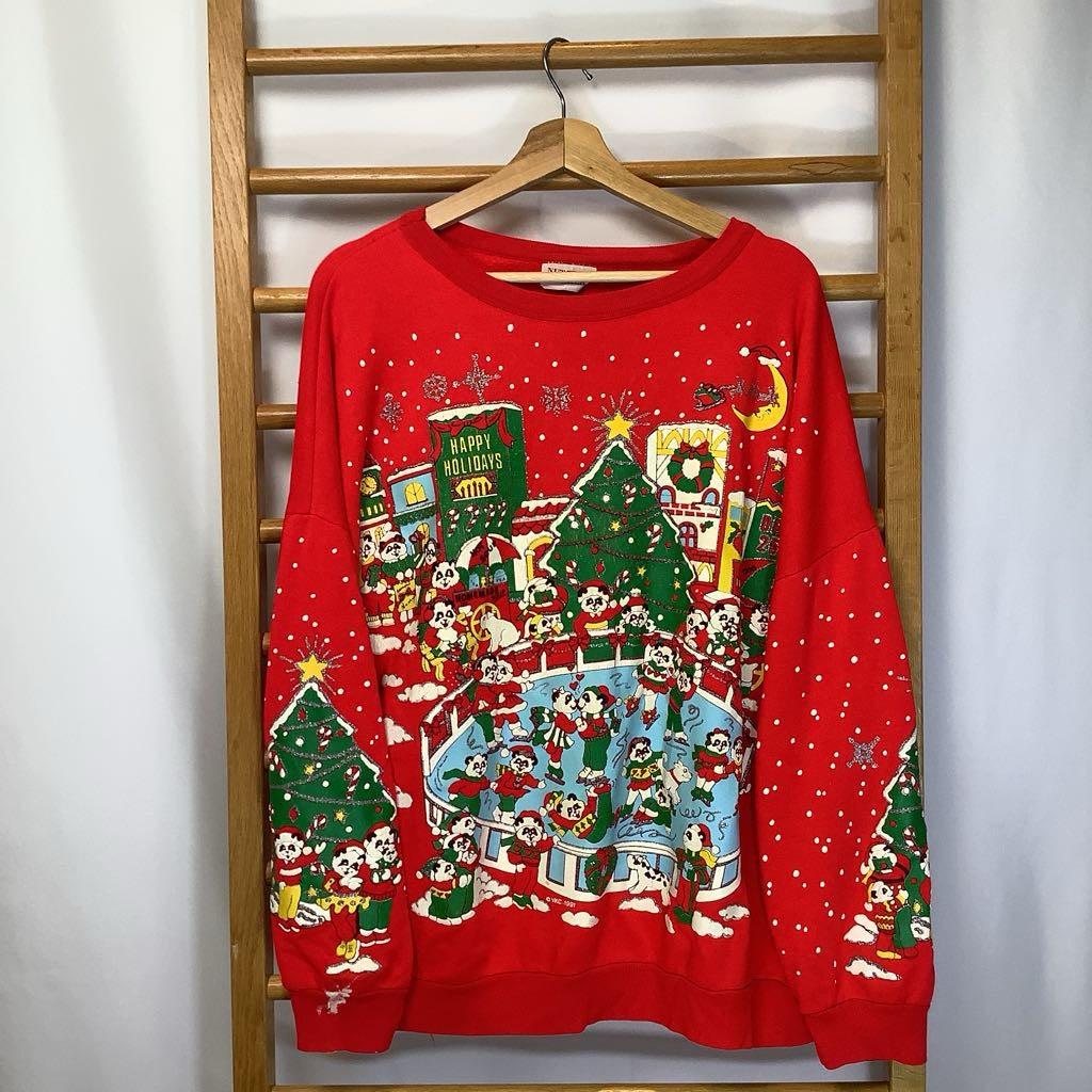 Red Christmas-themed sweater with festive design on a wooden hanger against a white wall.