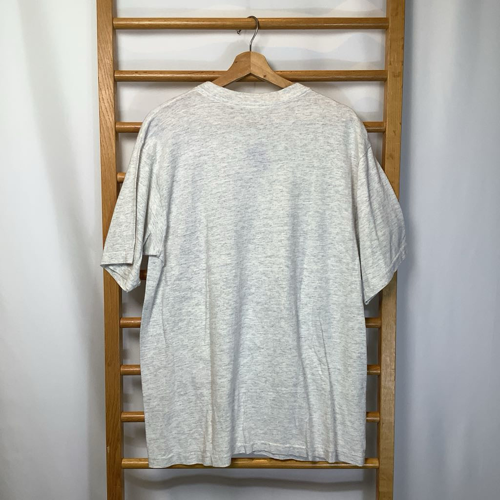 Gray t-shirt hanging on a wooden rack against a white wall