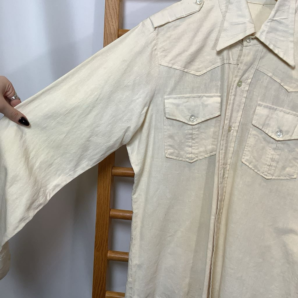 Beige shirt being held up against a white background
