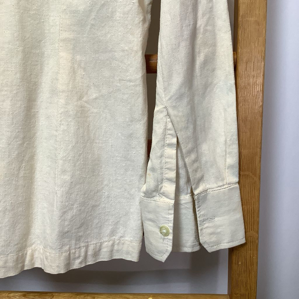 Light-colored shirt hanging on a wooden rack against a white wall