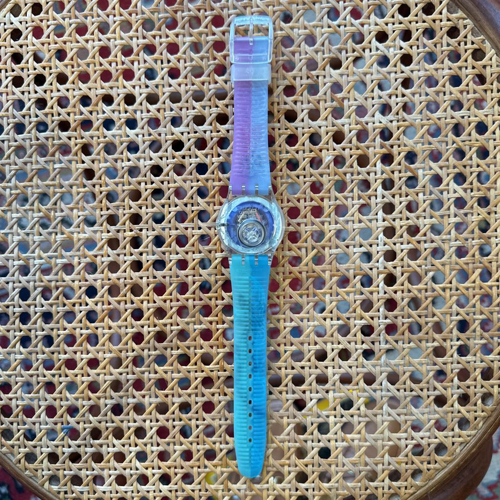 Watch with a blue strap and clear face on a wicker surface