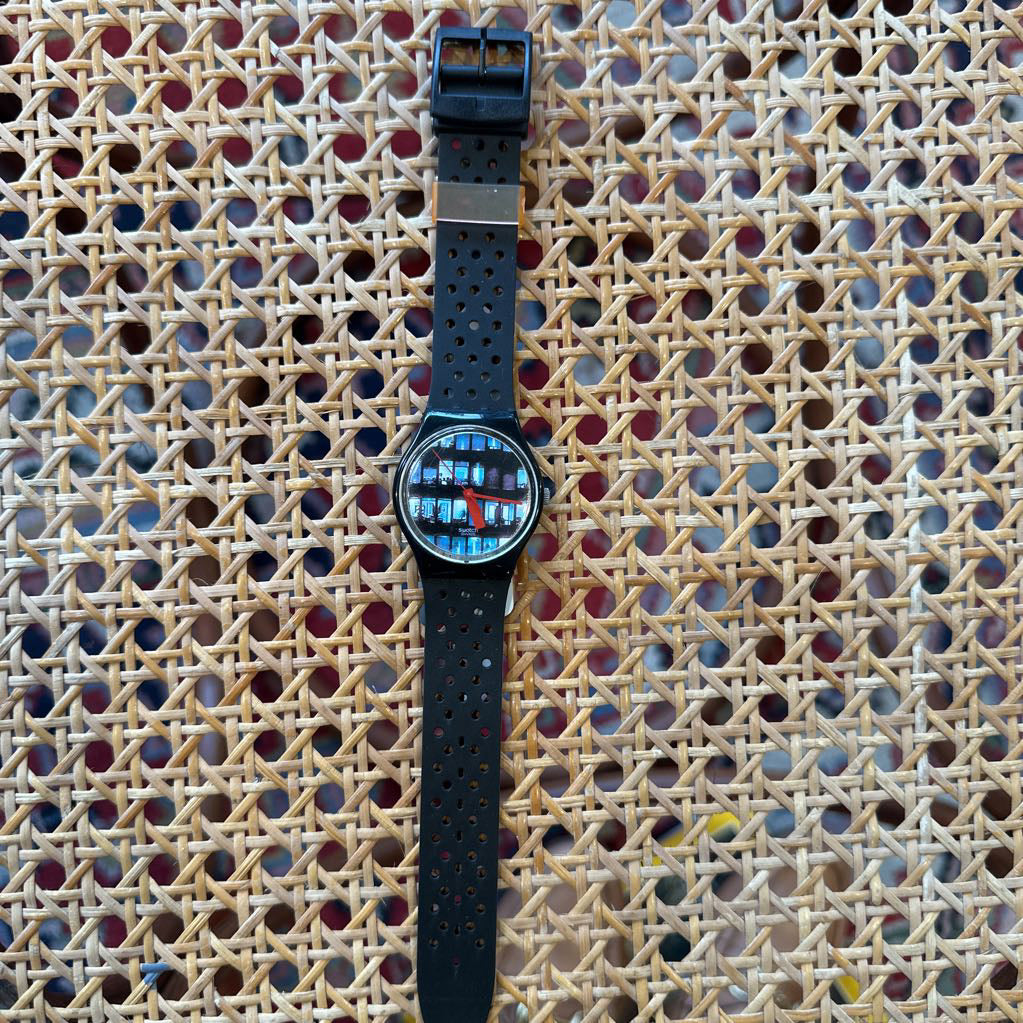 Wristwatch with a black strap on a textured woven surface