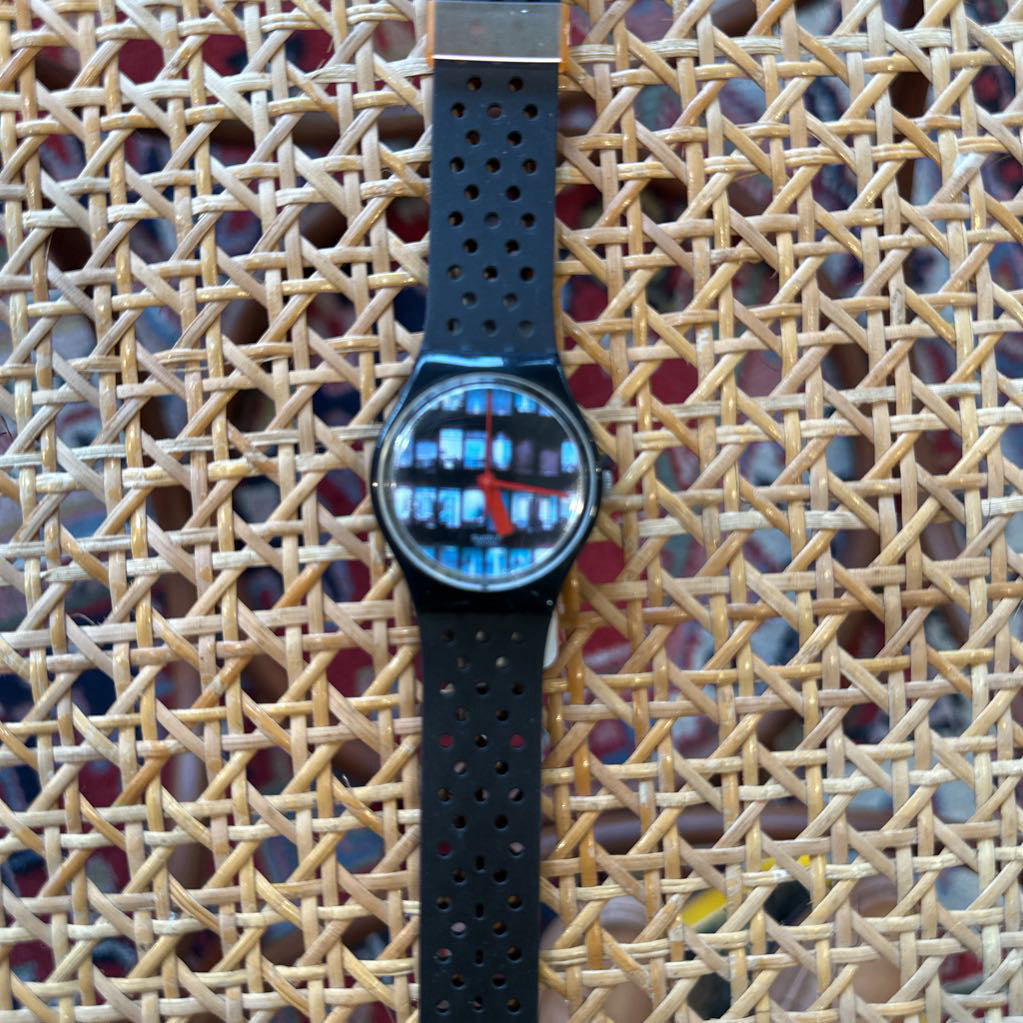 Wristwatch with a black strap on a textured woven surface