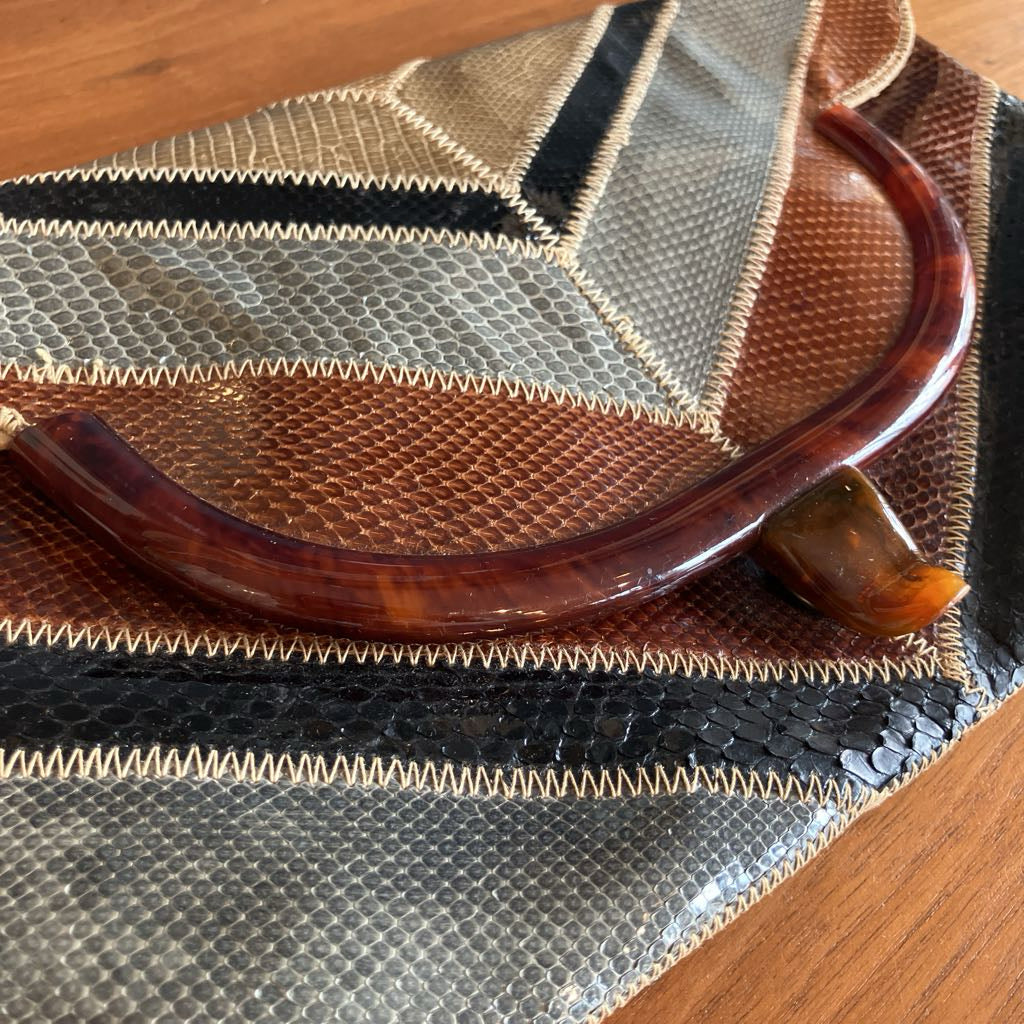 Snakeskin envelope bag on a wooden surface