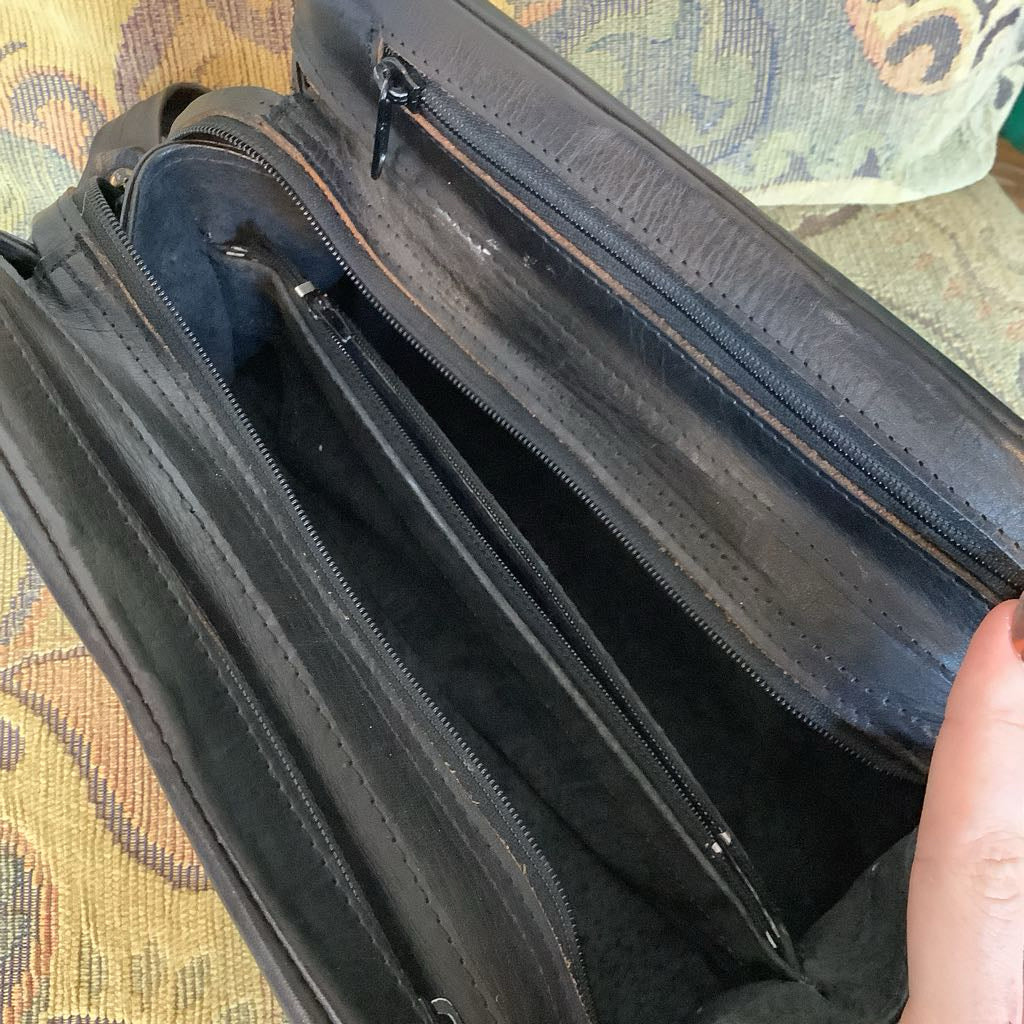 Black suitcase with a zipper open on a patterned fabric background