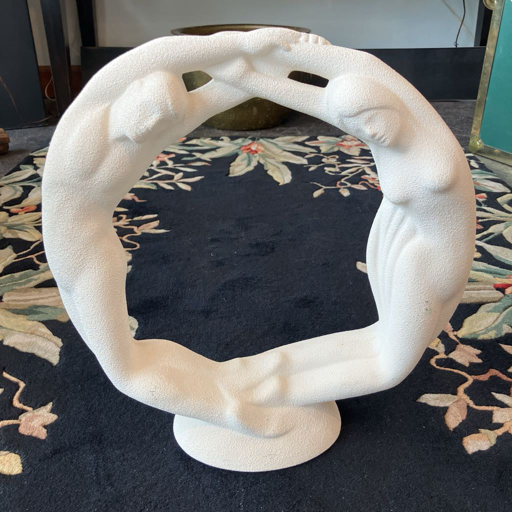 White circular sculpture on a dark surface with a floral pattern