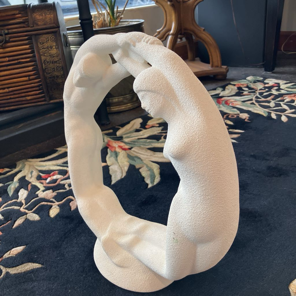 White abstract sculpture on a dark rug with decorative elements