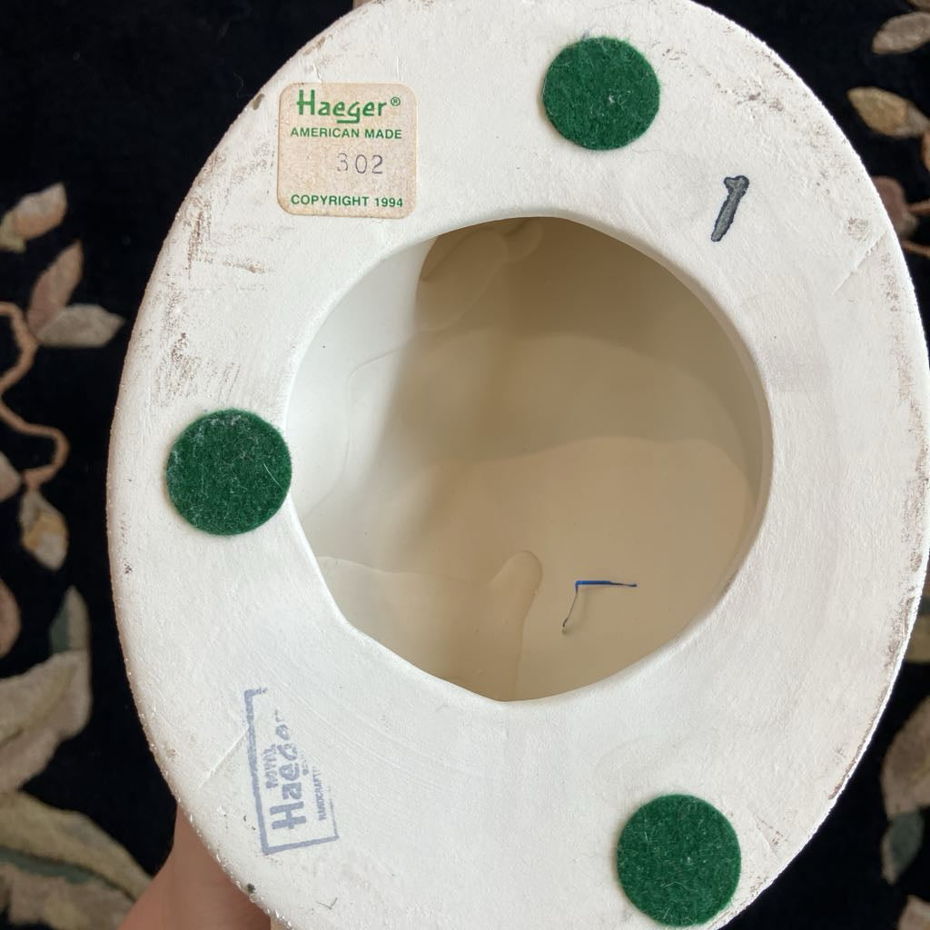 White ceramic base of sculpture with green felt dots and 'Haeger' branding on a dark background