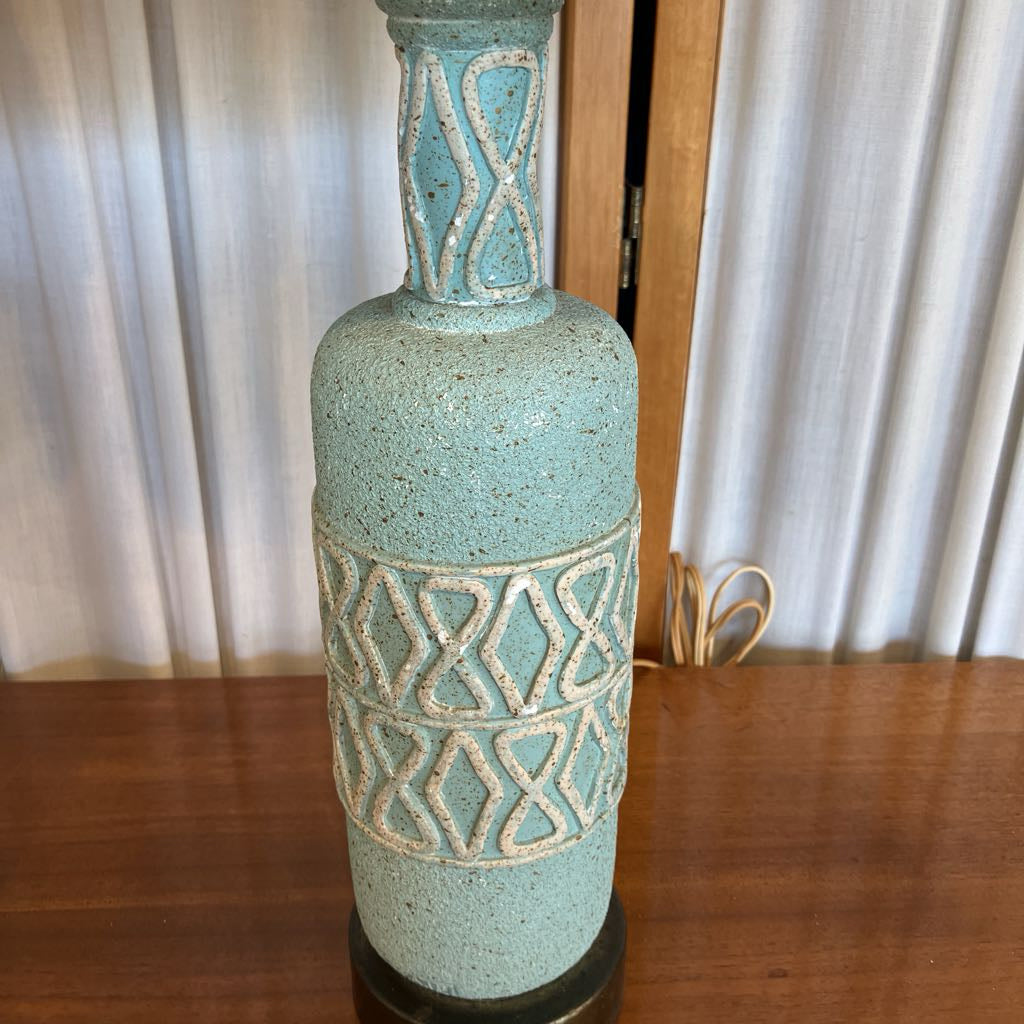 Teal ceramic lamp base with geometric patterns on a wooden surface
