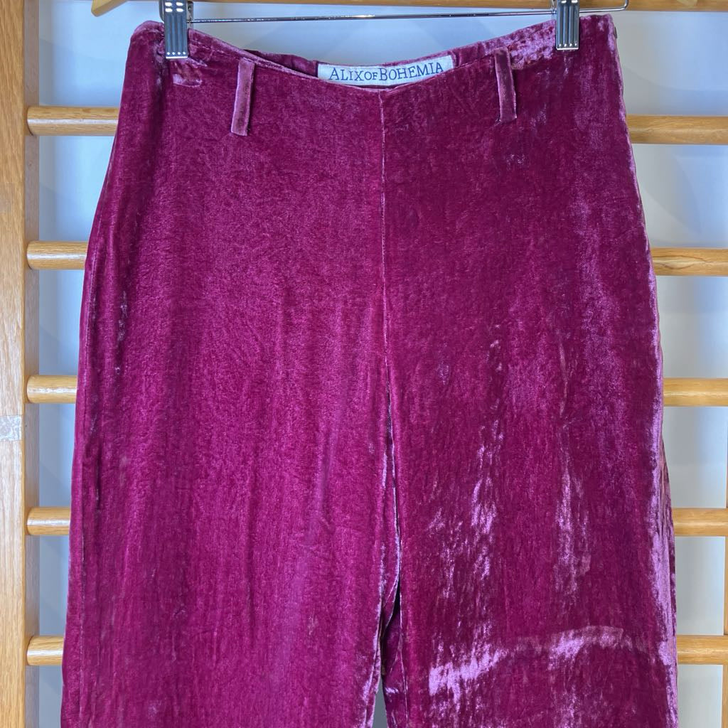 Maroon velvet pants hanging on a rack with 'Aiko of Bohemia' label.