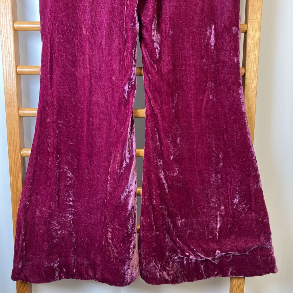 Pair of purple velvet pants on a wooden rack.