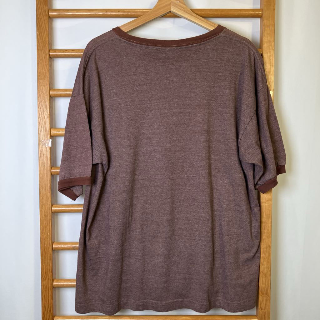 Brown shirt on a wooden hanger against a white wall