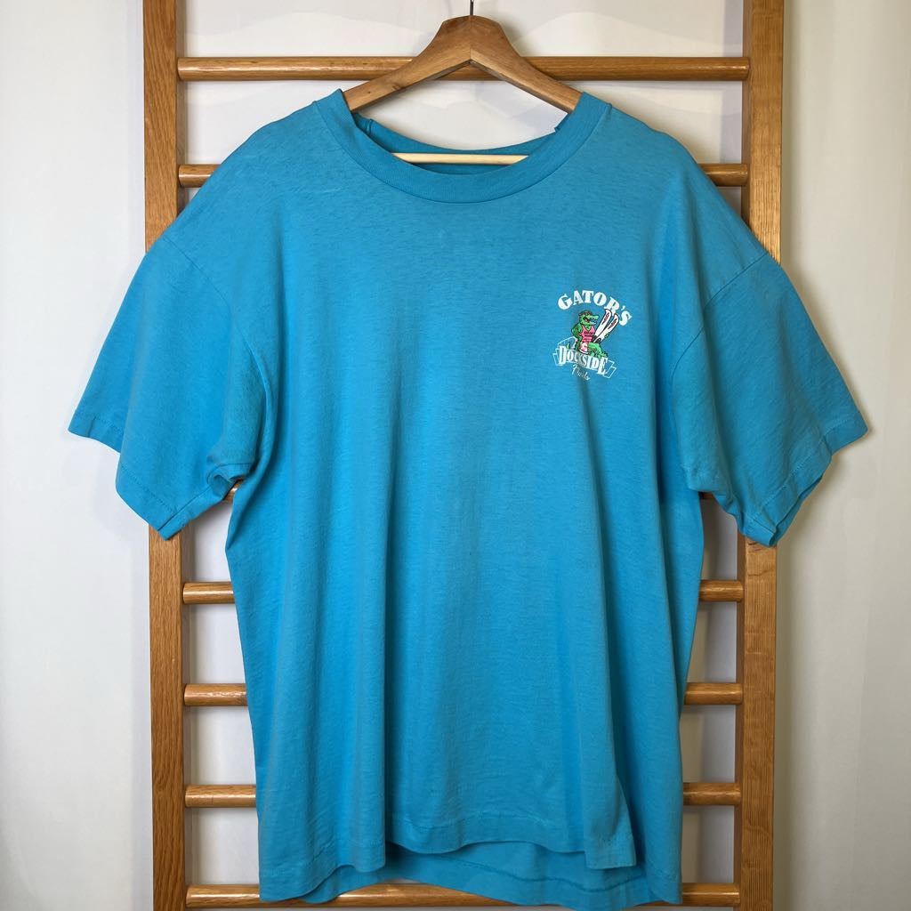 Blue t-shirt with a logo on a wooden hanger against a white wall