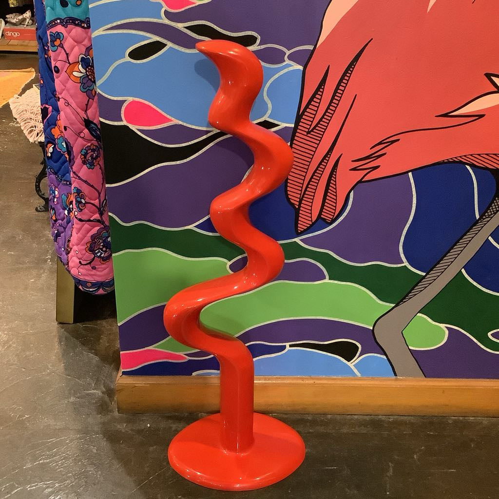 Red spiral sculpture in front of a colorful abstract painting