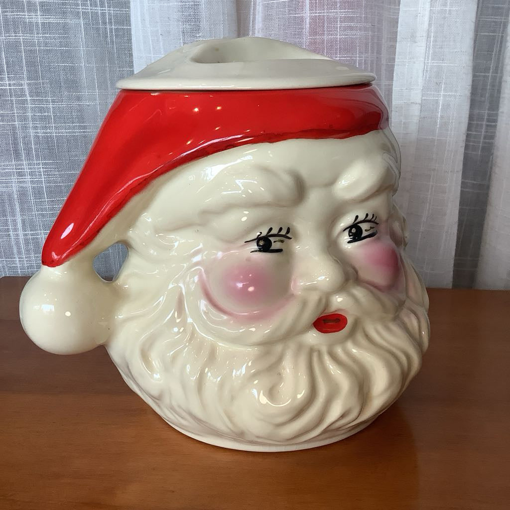 Ceramic cookie jar shaped like a Santa Claus face on a wooden surface.