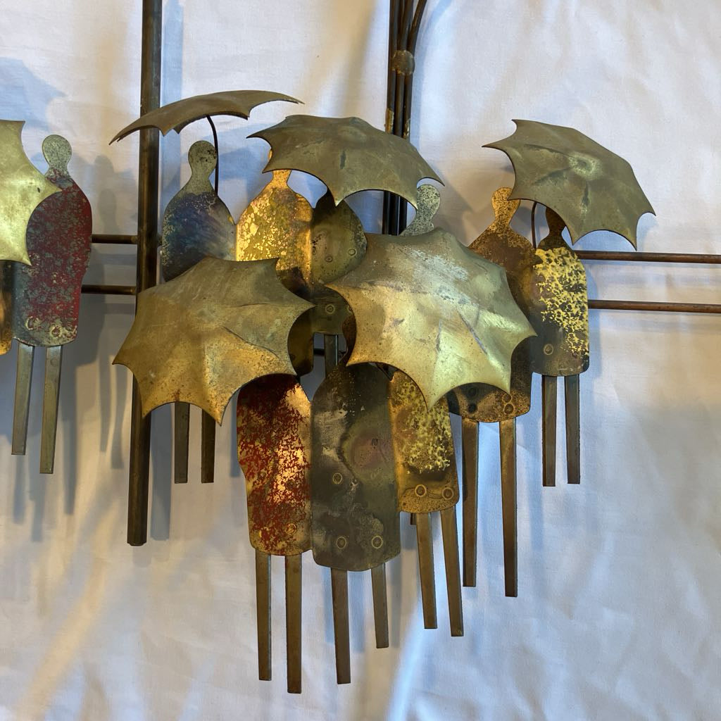 Metallic wall art with umbrellas and people on a textured white background