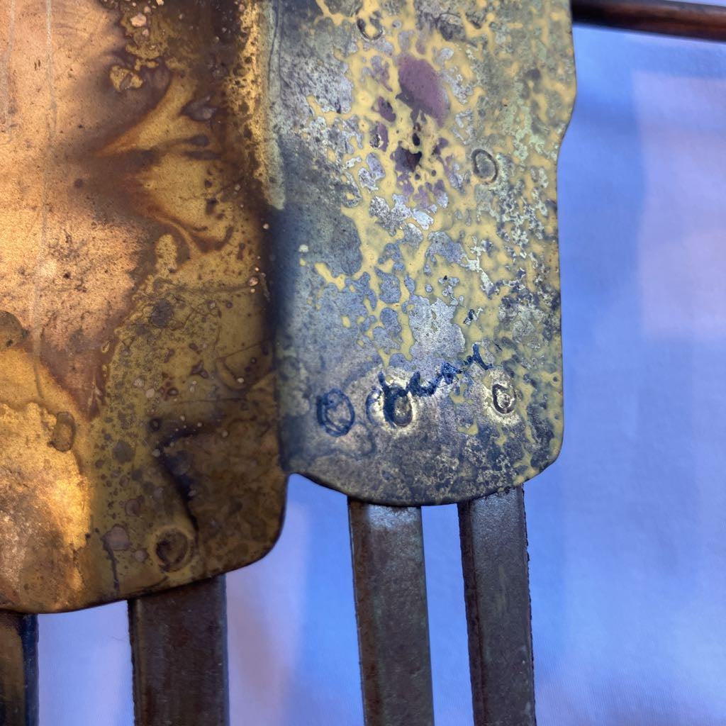 Metal object with artists signature on a white shadowed background