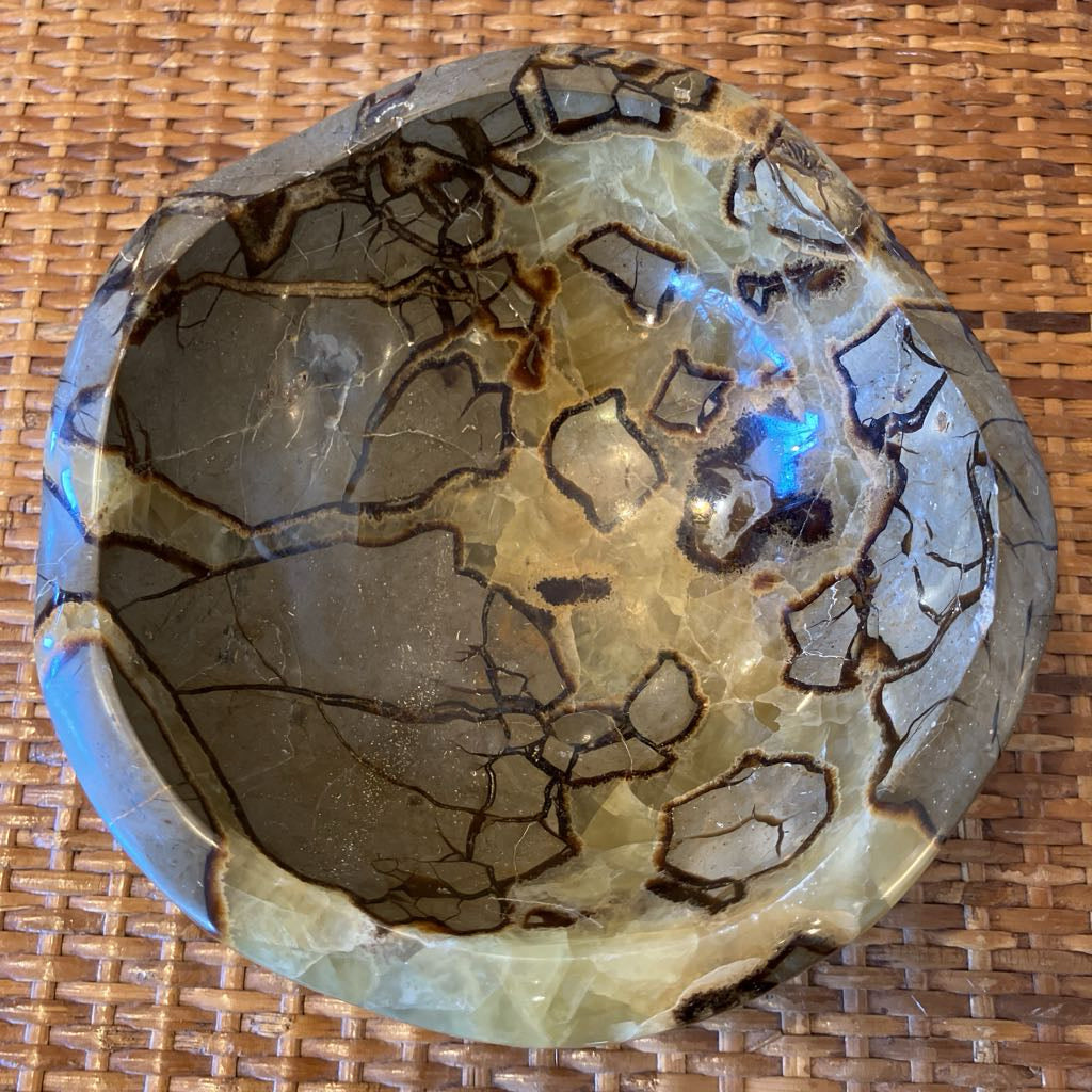Decorative stone bowl with brown and beige patterns on a woven surface