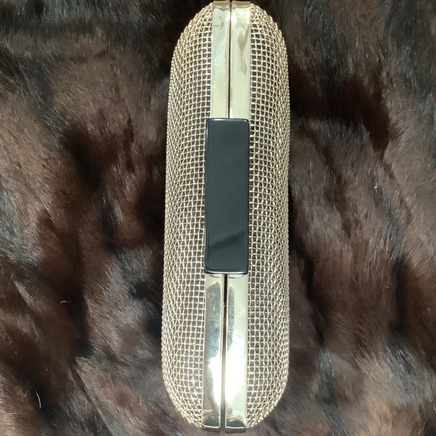 Gold mesh clutch bag on a fur surface