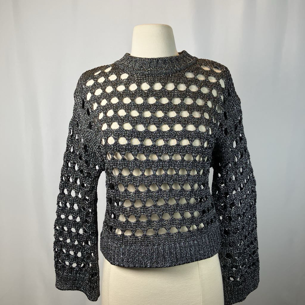 Black knit sweater with circular patterns on a mannequin against a plain background