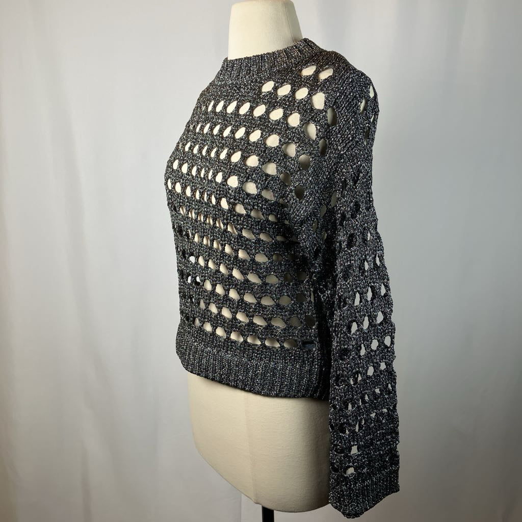 Mannequin wearing a black and white patterned sweater against a gray background