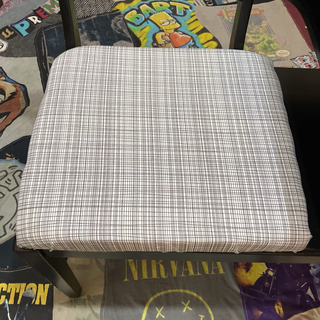 Plaid cushion on a chair with a colorful rug underneath