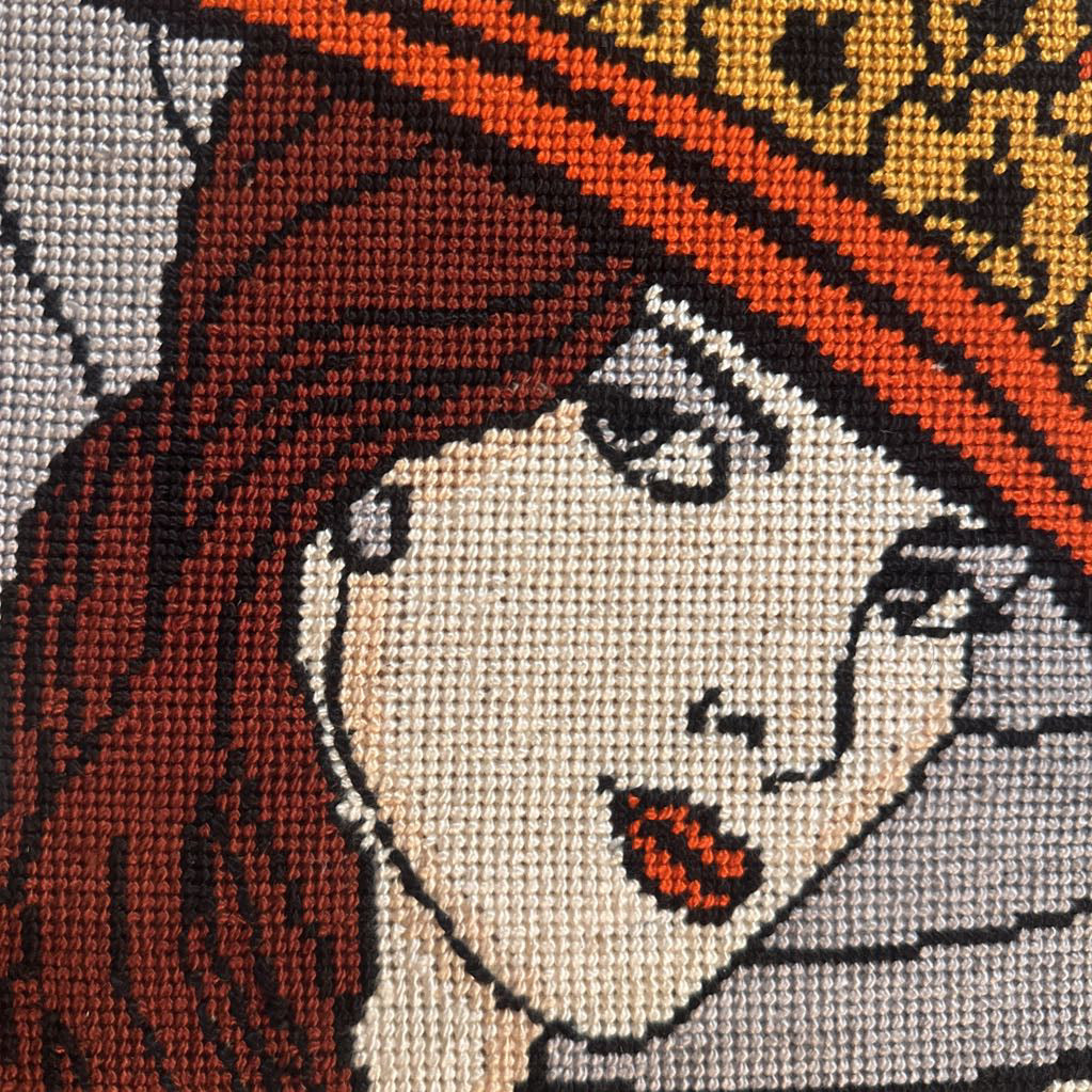 Close-up of a cross-stitched portrait with intricate details