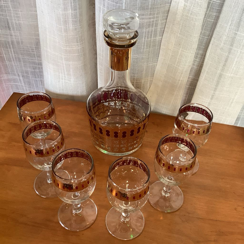 Set of glass decanter and tumblers with gold accents on a wooden table.