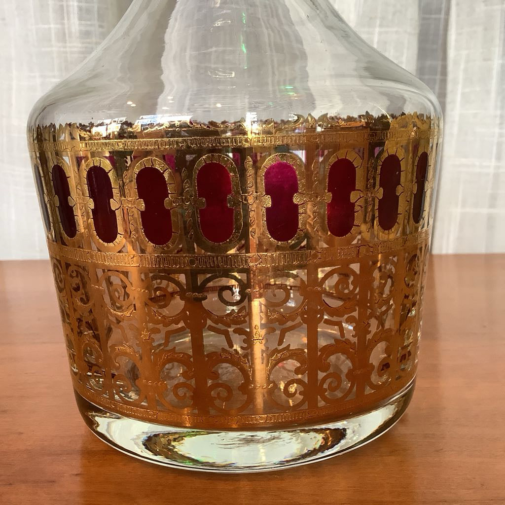 Decorative glass decanter with gold intricate design on a wooden surface
