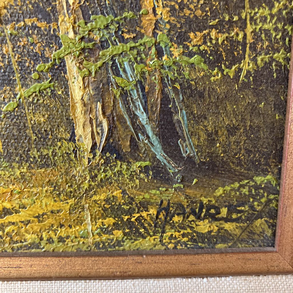 Close-up of a textured painting with a signature, featuring earthy tones and a wooden frame.