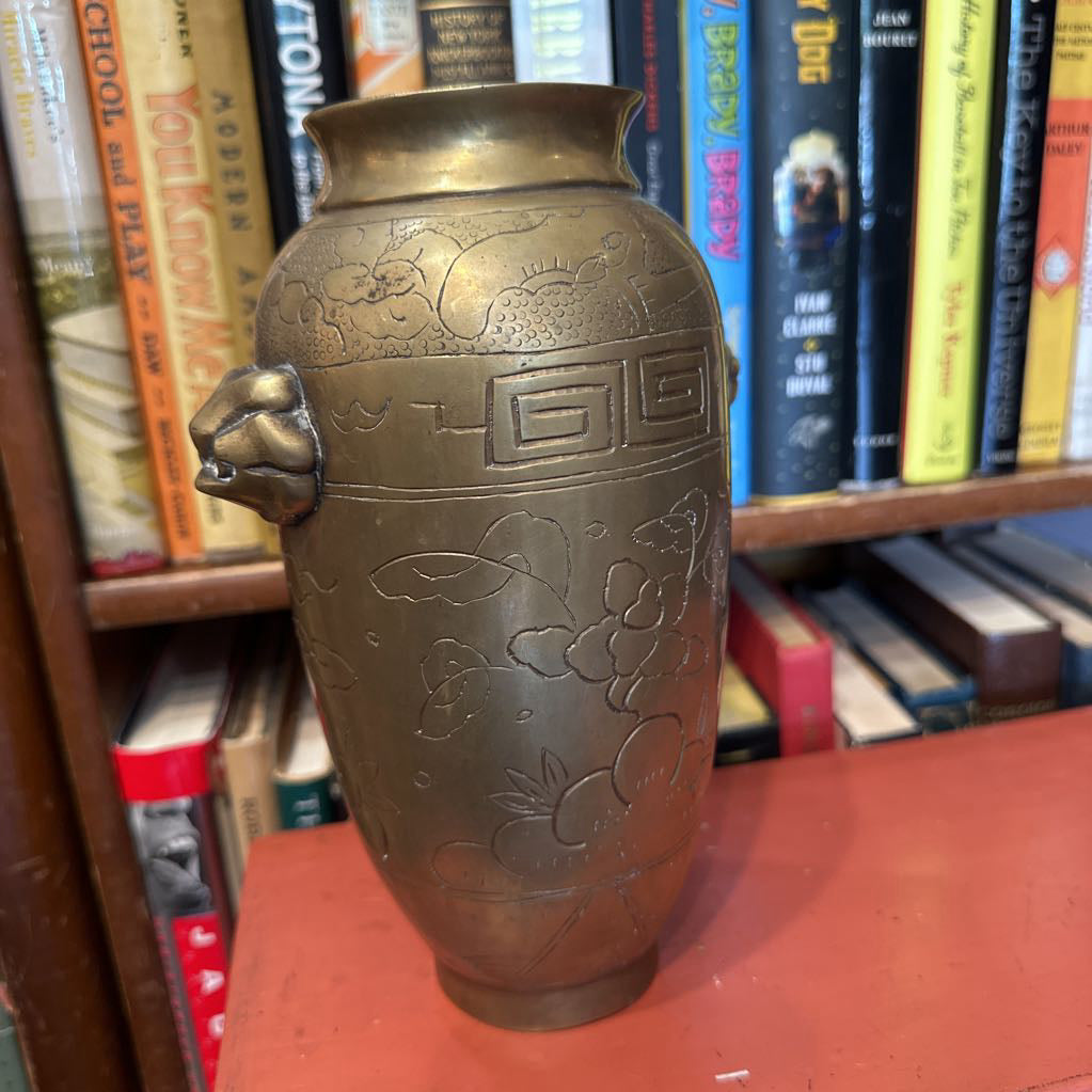 Bronze vase with floral patterns on a bookshelf