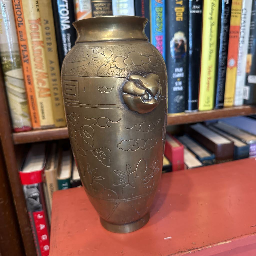 Bronze vase with floral patterns on a bookshelf