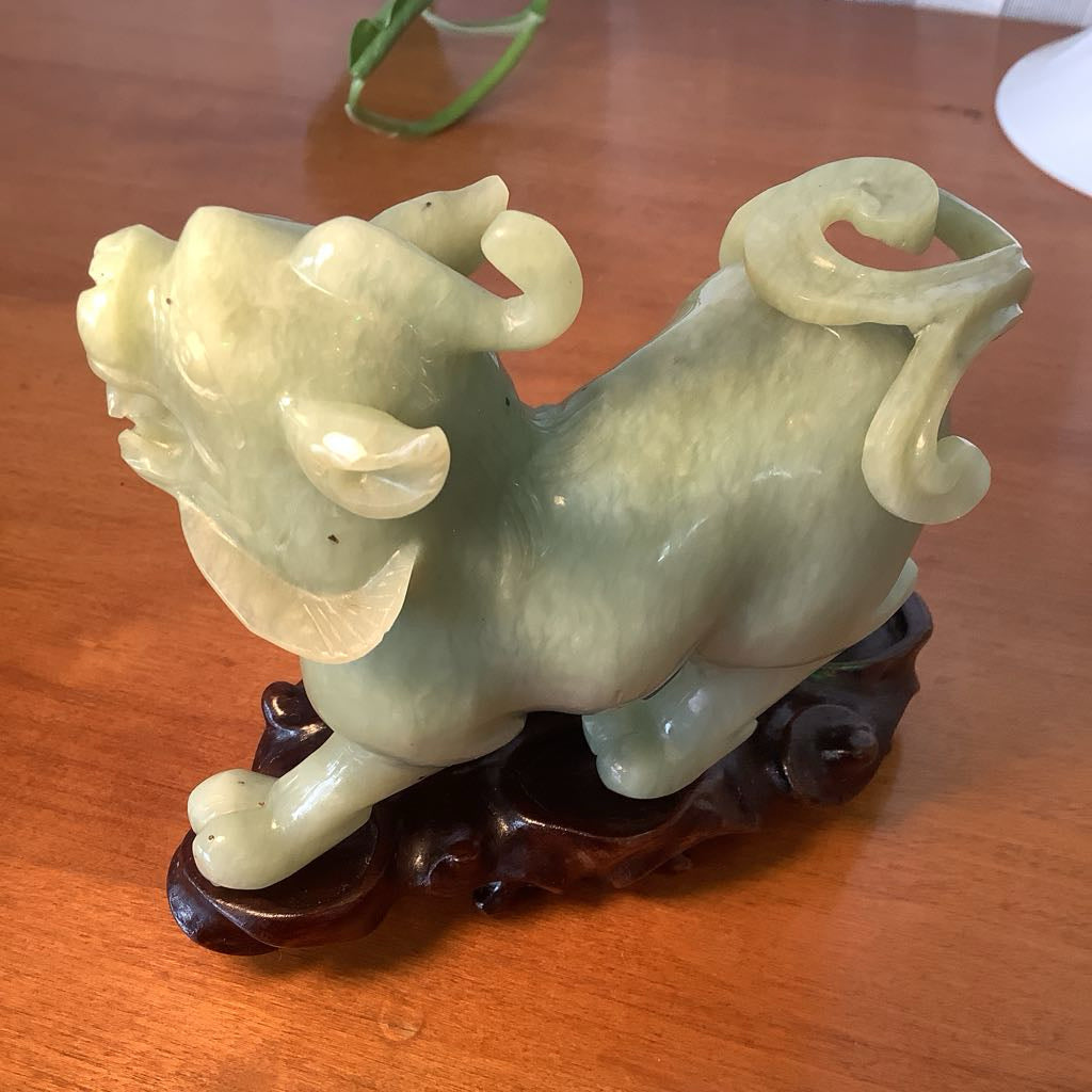 Green jade sculpture of a mythical creature on a wooden stand