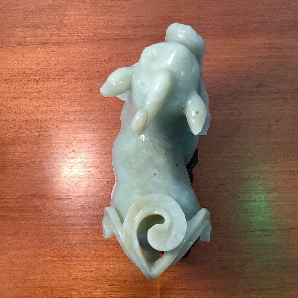 White jade sculpture of a dog on a wooden surface