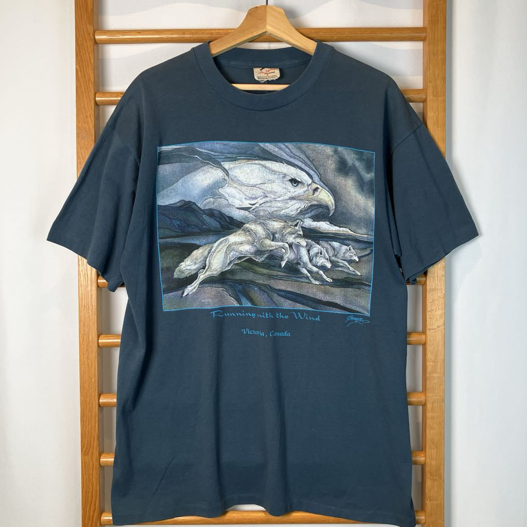 Navy blue t-shirt with an eagle and wolf graphic on a wooden rack