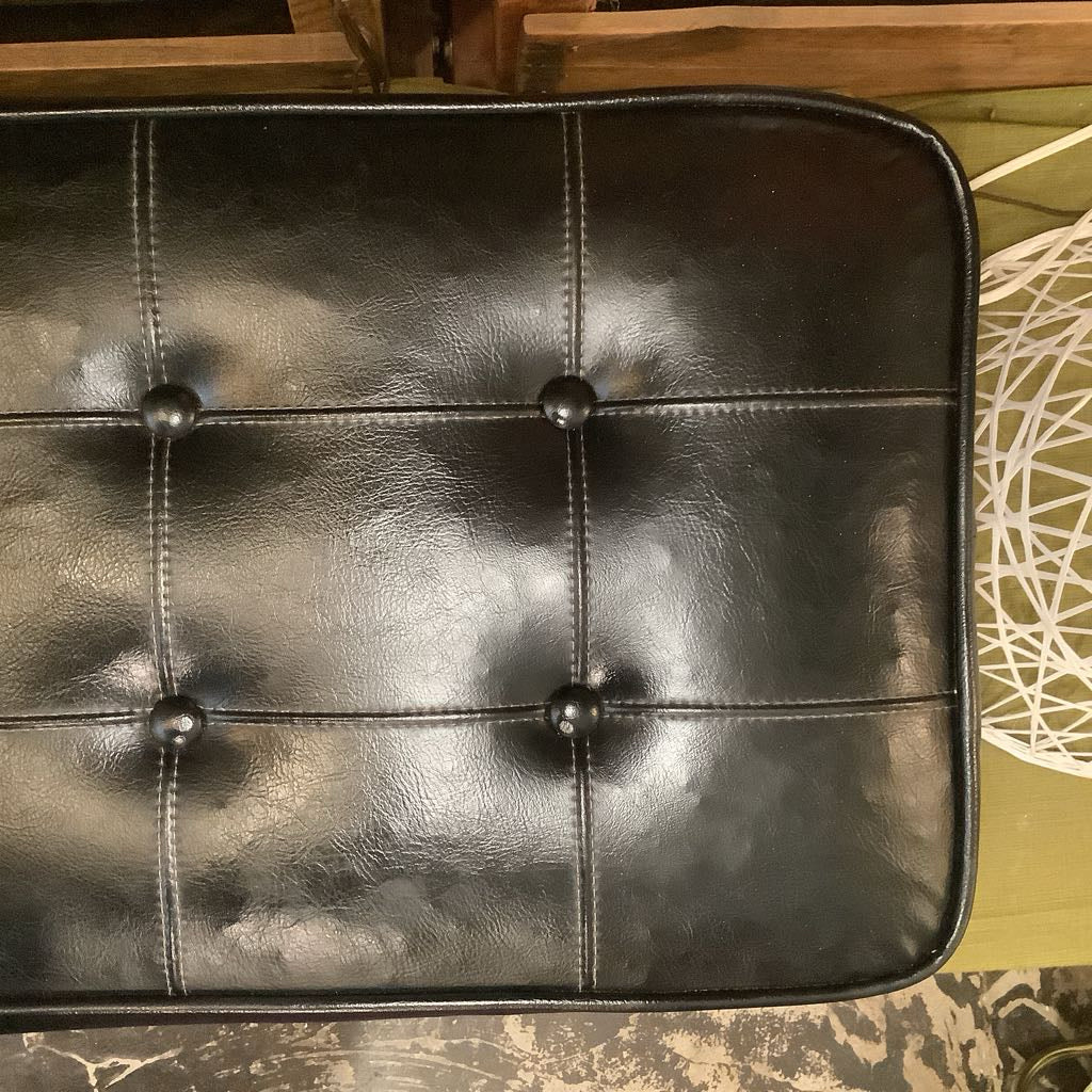 Black leather pouch with button details on a textured surface