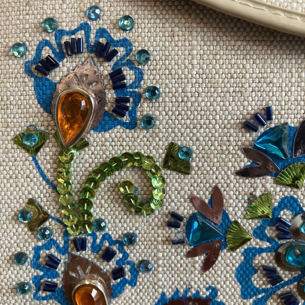 Close up of colorful beadwork on a beige handbag
