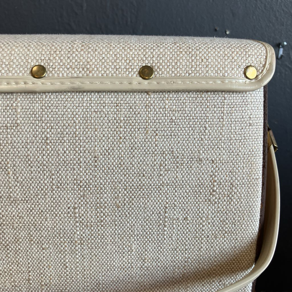 Beige handbag with gold studs on a dark background