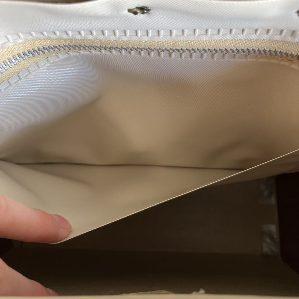 Close-up of a beige bag with a hand opening it