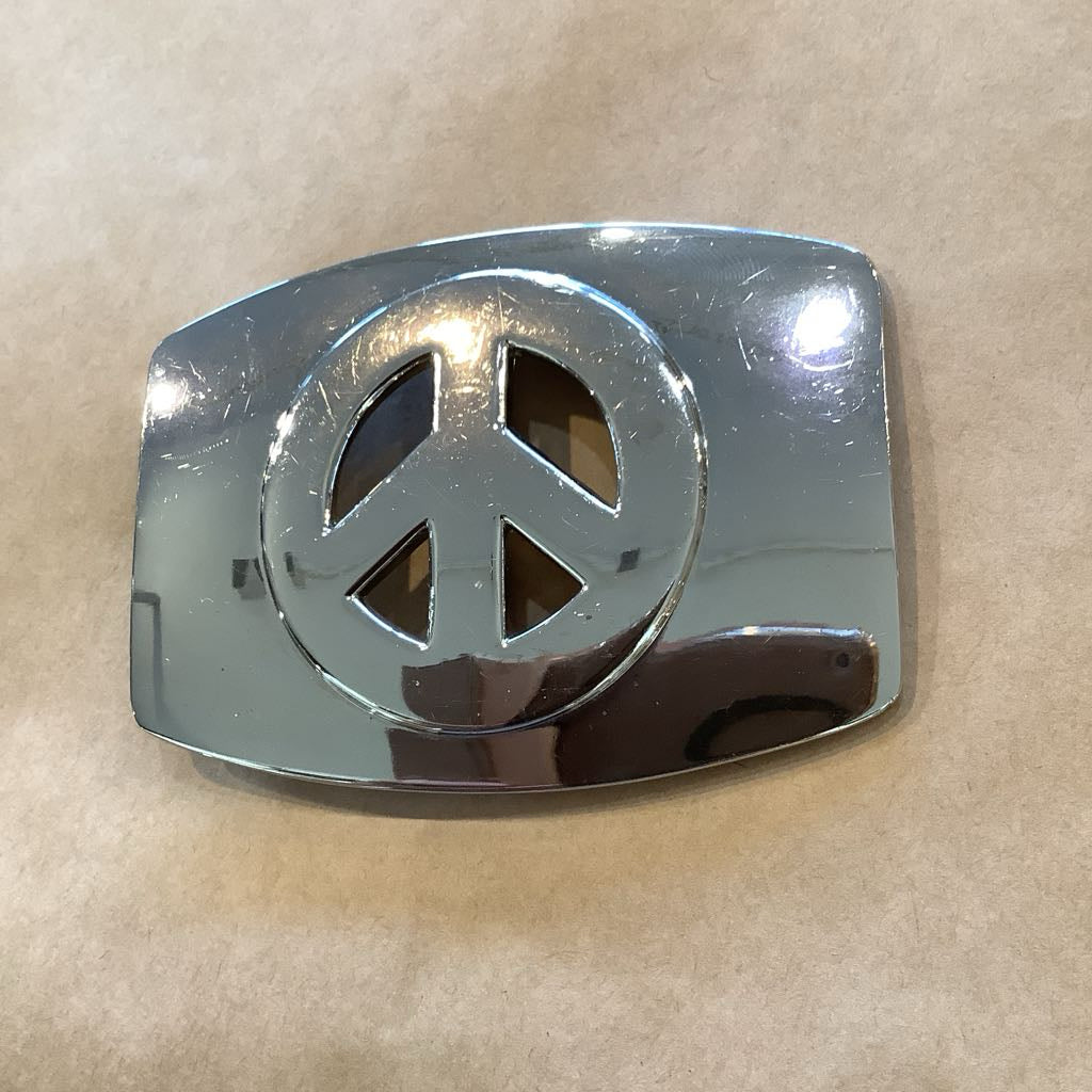 Chrome peace symbol belt buckle on a beige background