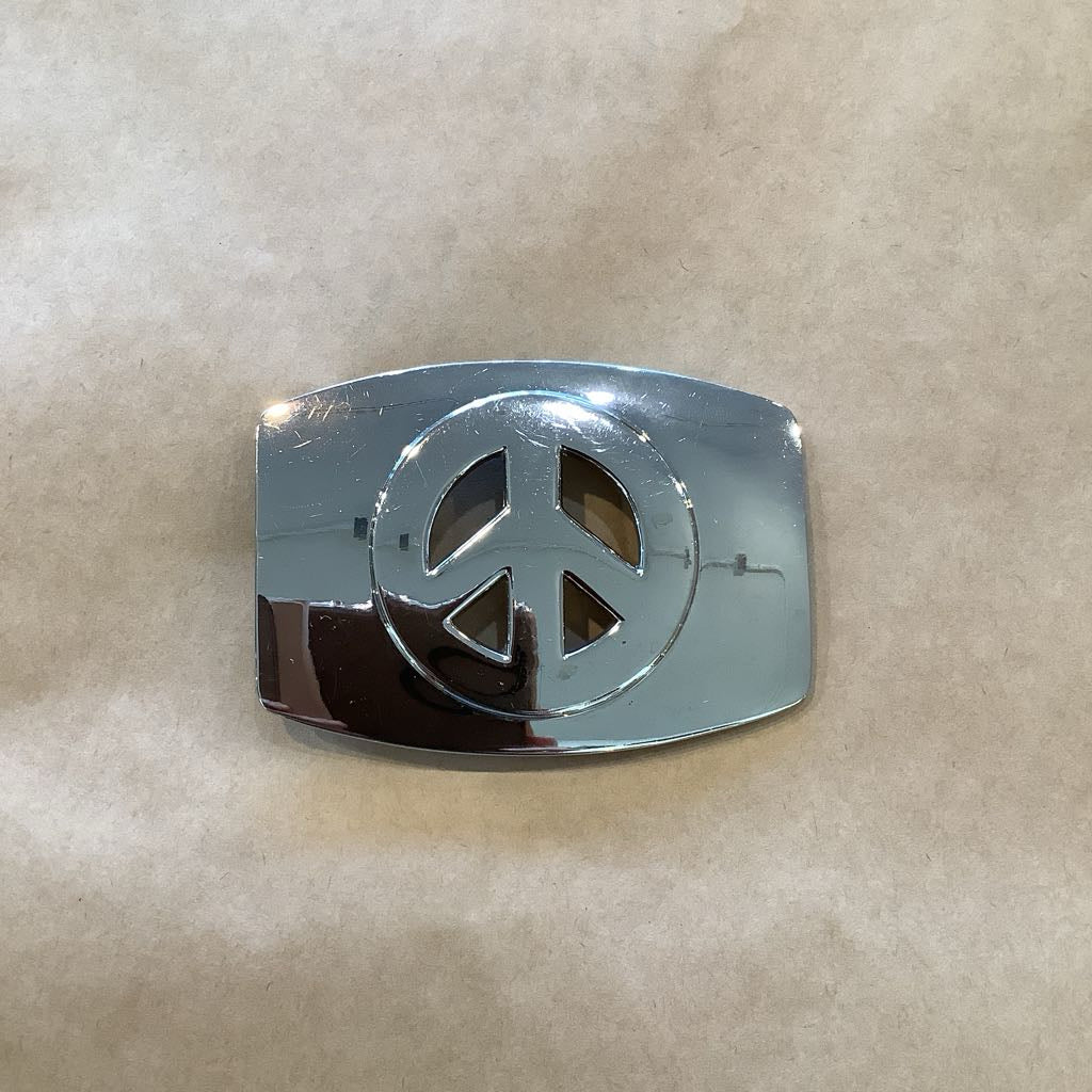 Chrome peace symbol belt buckle on a beige background