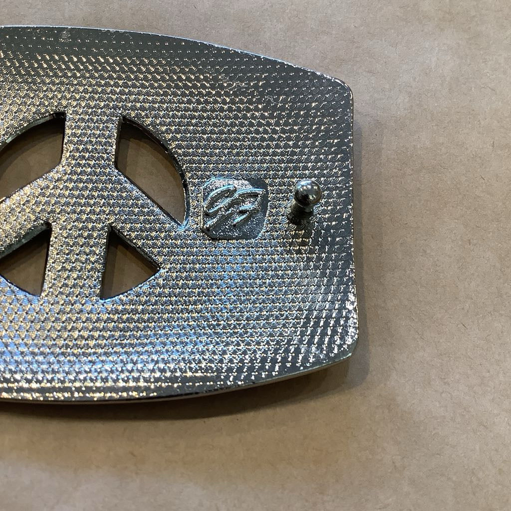 Metallic peace symbol object on a beige background