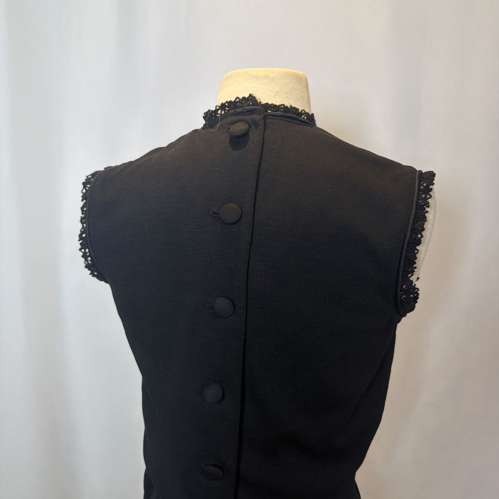 Black dress with lace trim on a mannequin against a white background