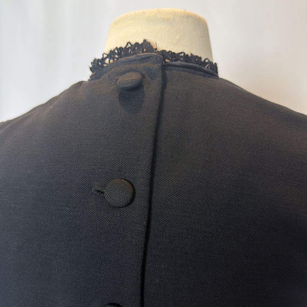 Black dress with lace trim on a mannequin against a white background