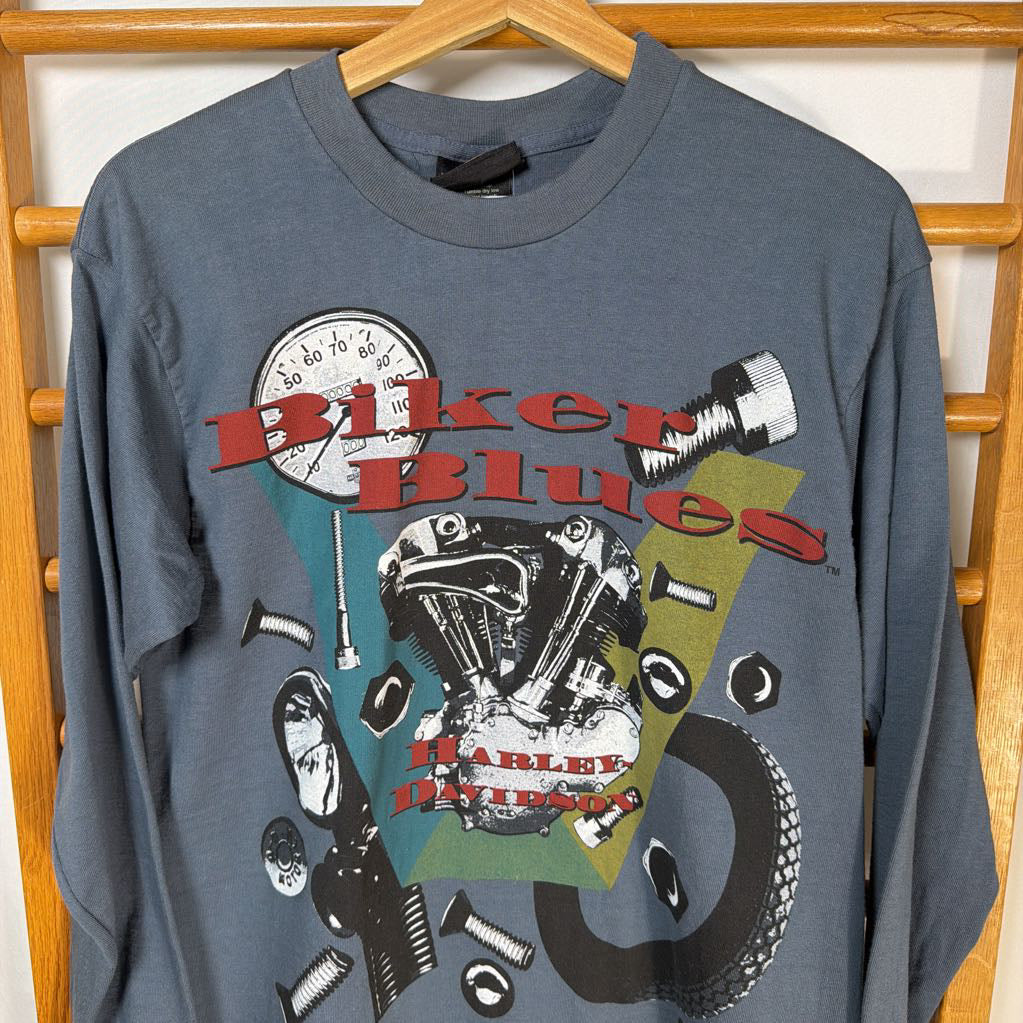 Gray sweatshirt with 'Biker Blues' and Harley Davidson graphics on a wooden rack.