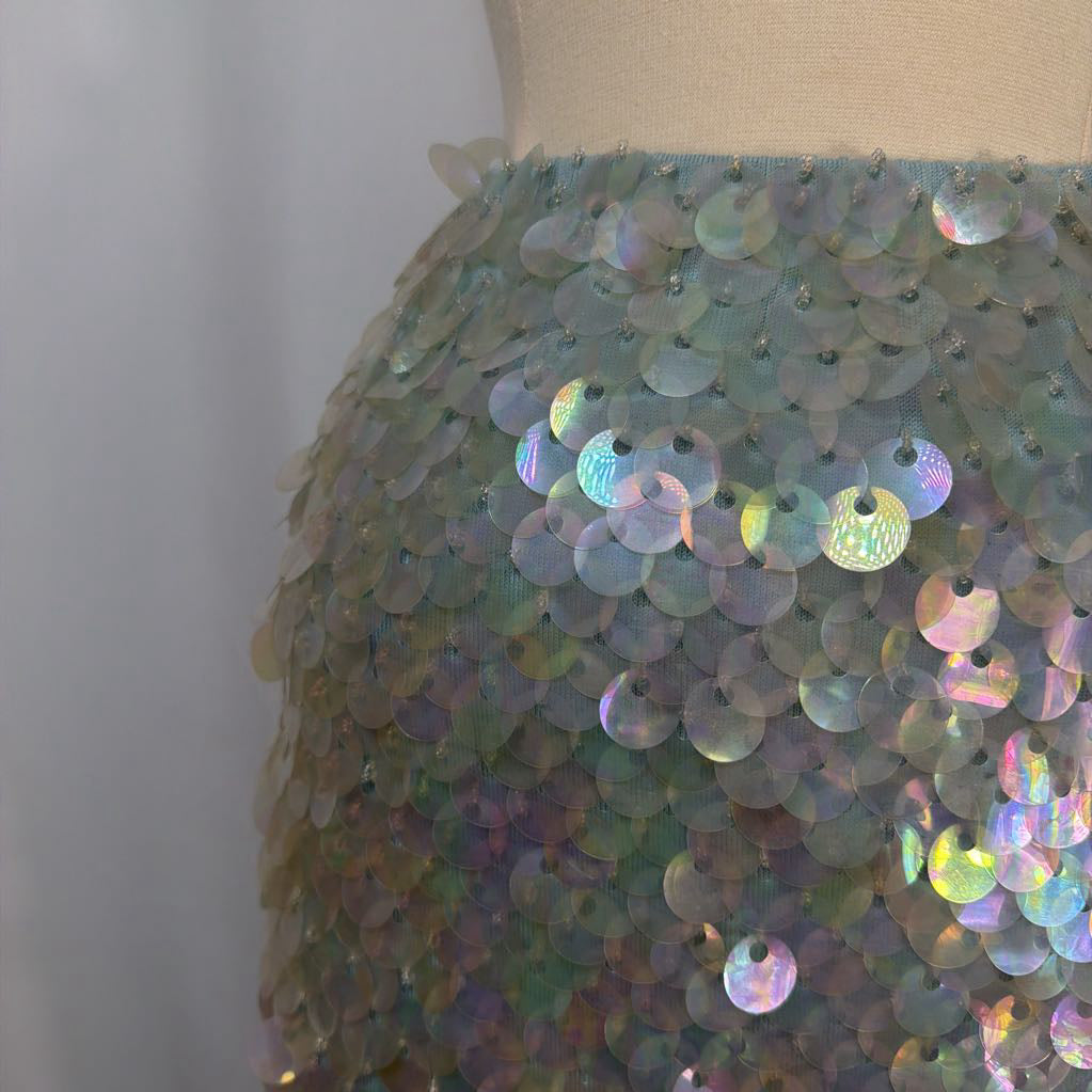 Close-up of a dress with iridescent sequins on a mannequin against a plain background