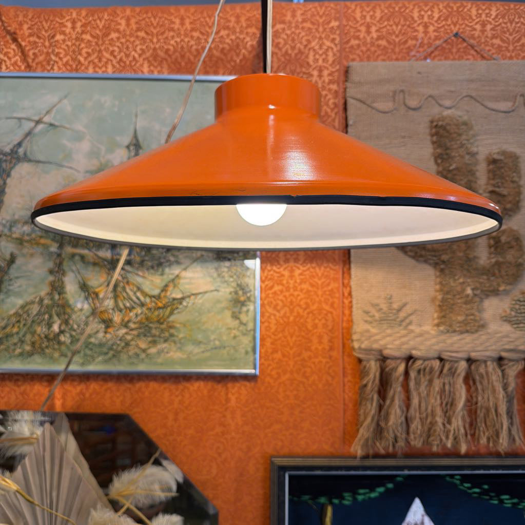 Orange pendant light hanging in a room with decorative elements.